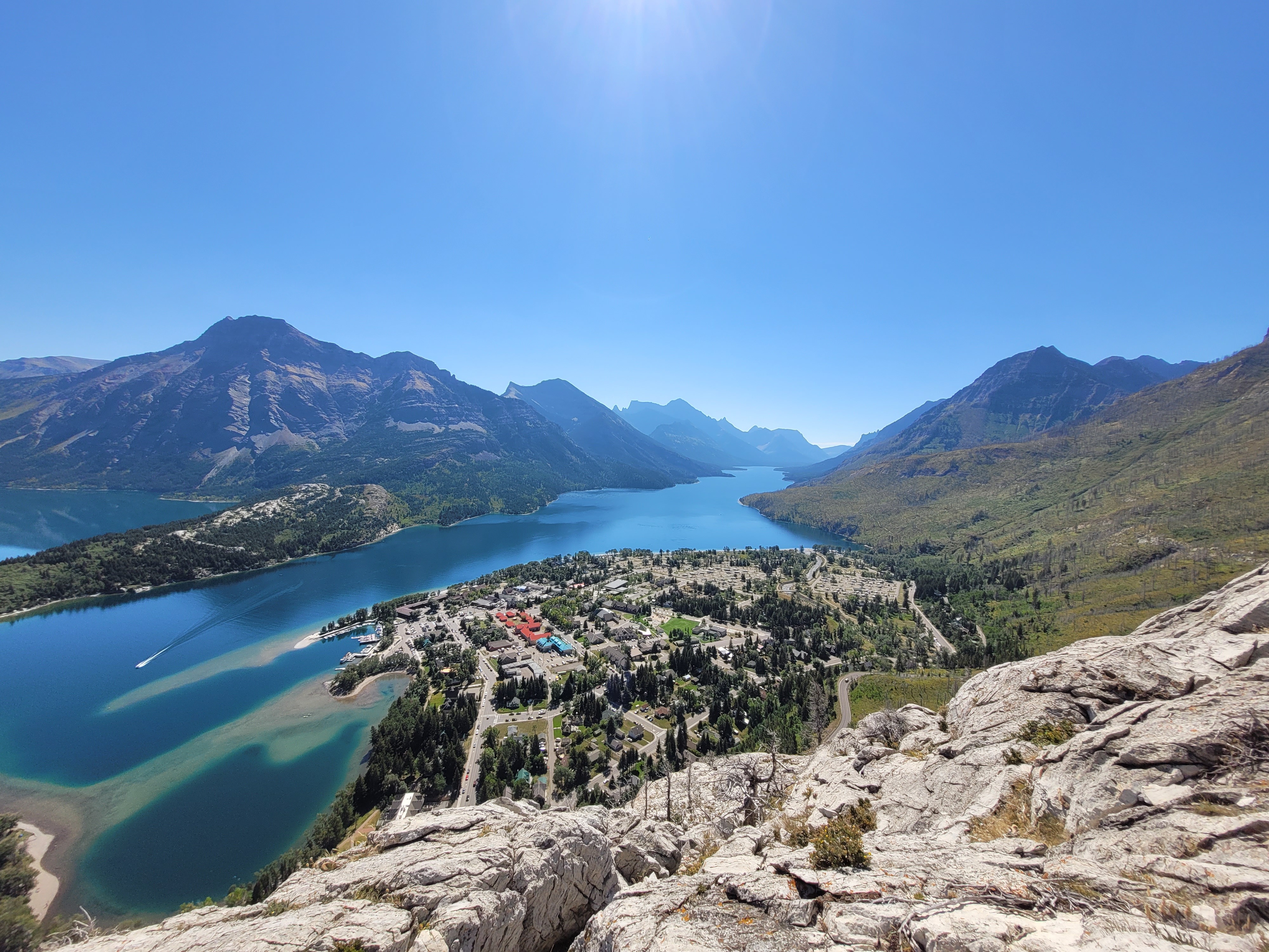Overlooking the stunning Waterton Lakes in Alberta, Canada, surrounded by majestic mountains and a serene village below.