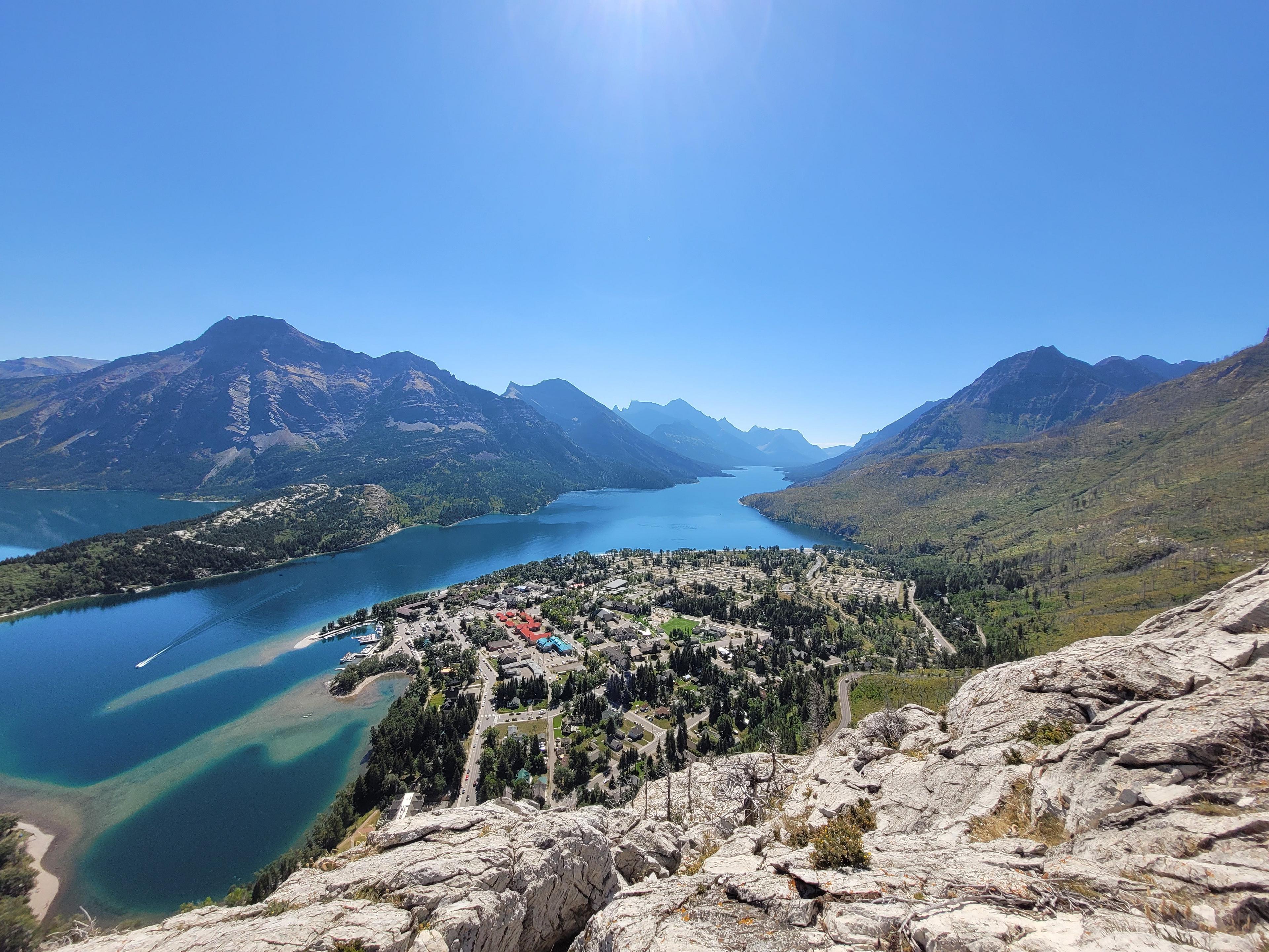 Overlooking the stunning Waterton Lakes in Alberta, Canada, surrounded by majestic mountains and a serene village below.