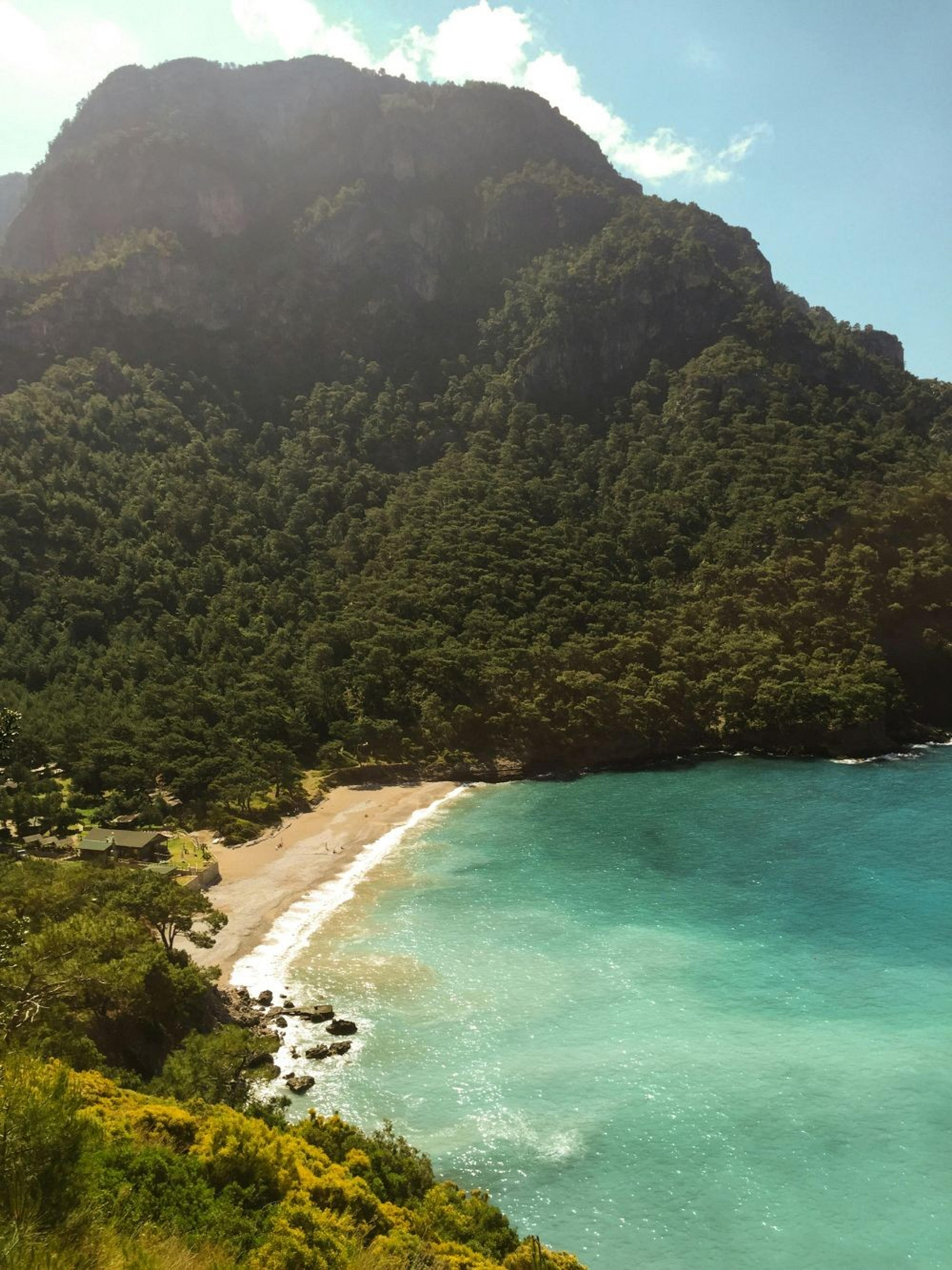 A stunning view of Kabak Bay in Turkey, featuring turquoise waters bordered by lush green hillsides.