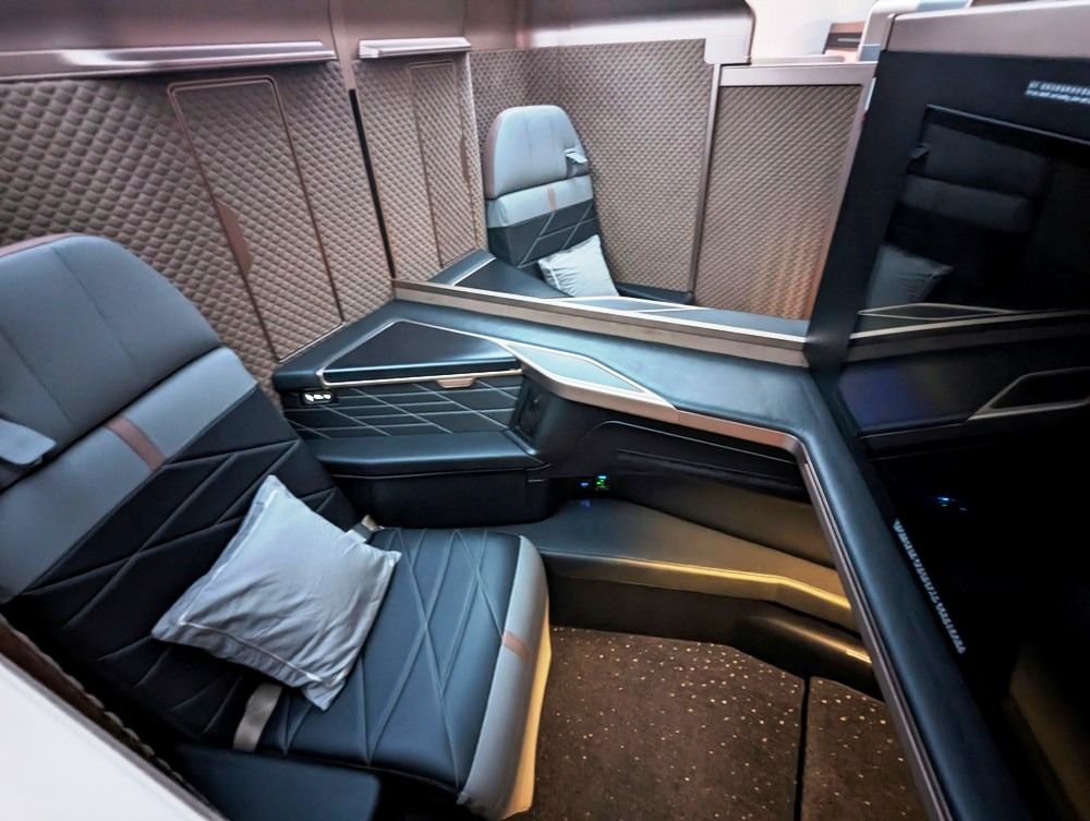 A luxurious airline first-class suite with sleek, modern design and plush seating likely from an aircraft's upper-class section.
